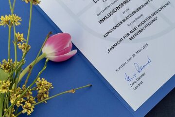 Urkunde mit einem Blumenstrauß. Text: Urkunde. Landkreis Konstanz. Der Landkreis Konstanz verleiht den Inklusionspreis 2024 an die Konstanzer Blätzlebuebe Zunft e.V. für das Projekt Fasnacht für alle auch für Menschen mit Beeinträchtigung. Konstanz den 19. März 2025. Zeno Danner.